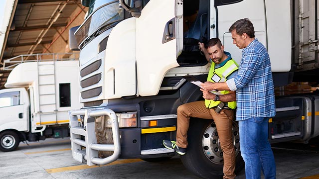 Técnico realiza manutenção preventiva em caminhão como parte da política de segurança da frota para evitar falhas mecânicas e aumentar a eficiência operacional em transportes.