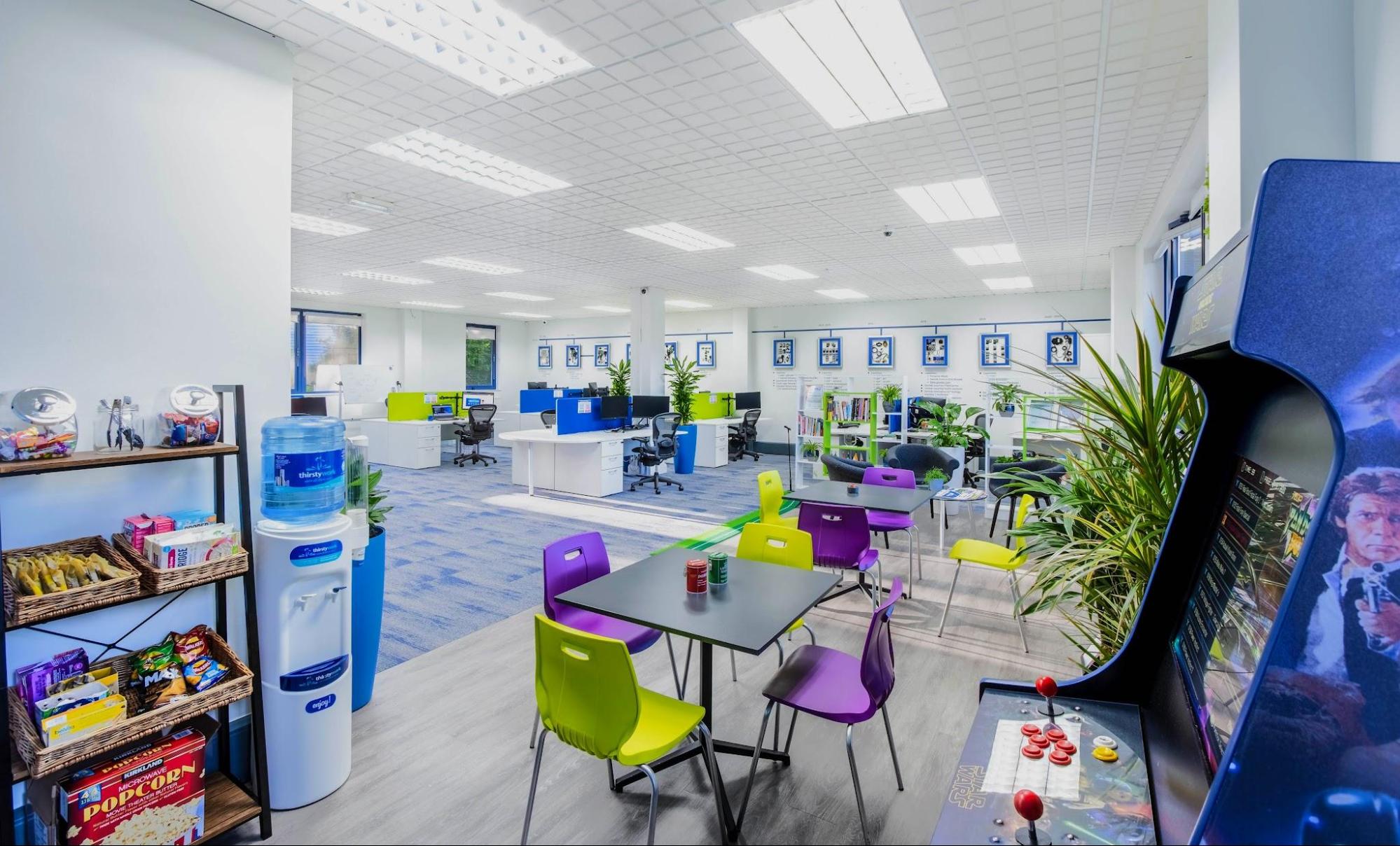 An image showing Geotab’s High Wycombe office, featuring snacks, colorful tables and chairs, plants and a Star Wars arcade game.