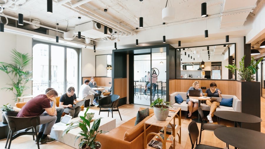 An image of the co–working space Parisian Geotabbers work out of with couches, tables, plants, and overhead lighting fixtures.