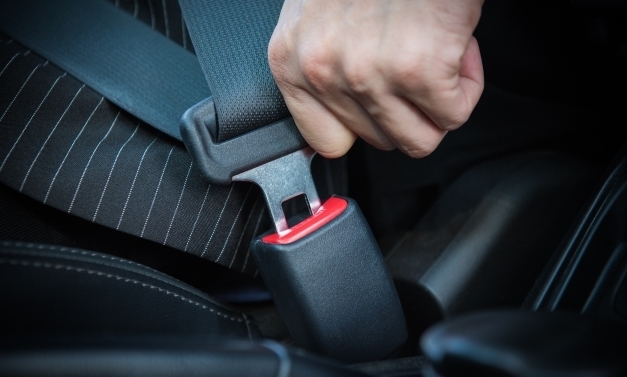Image of a driver buckling their seat belt.