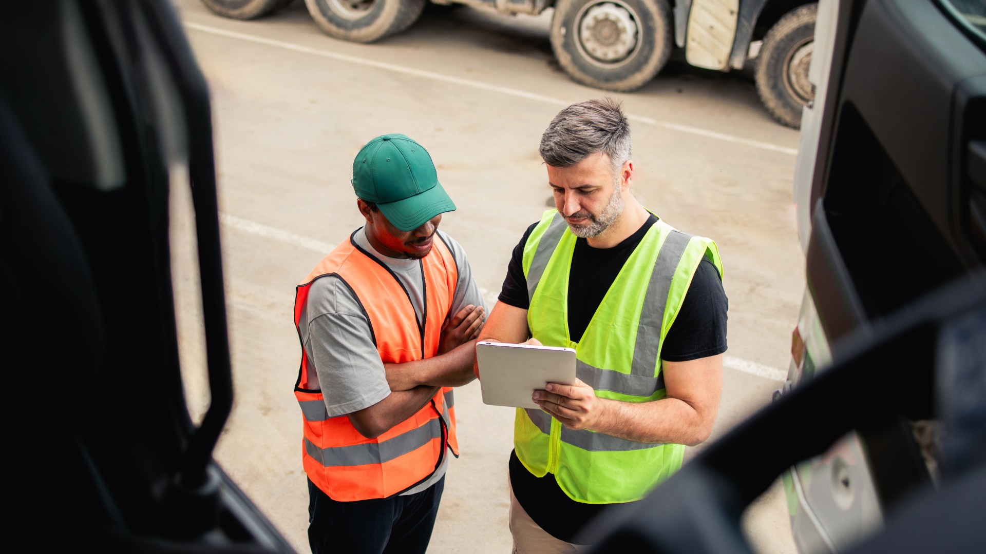 two people in vests looking at a tablet