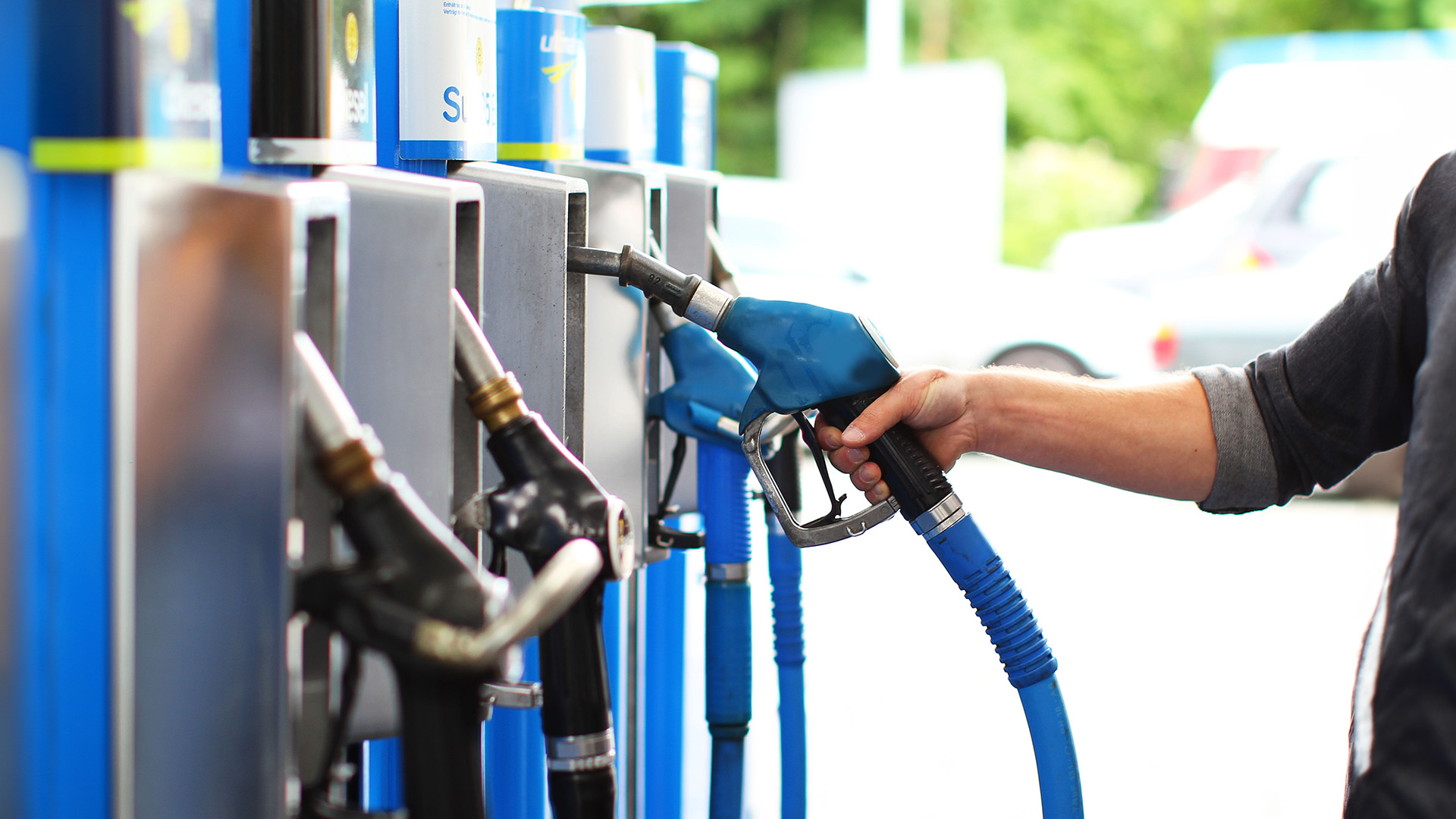 person putting back a fuel nozzle