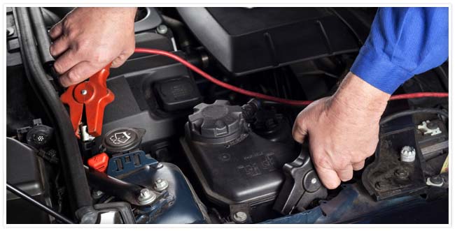 Driver using jumping cables on car battery