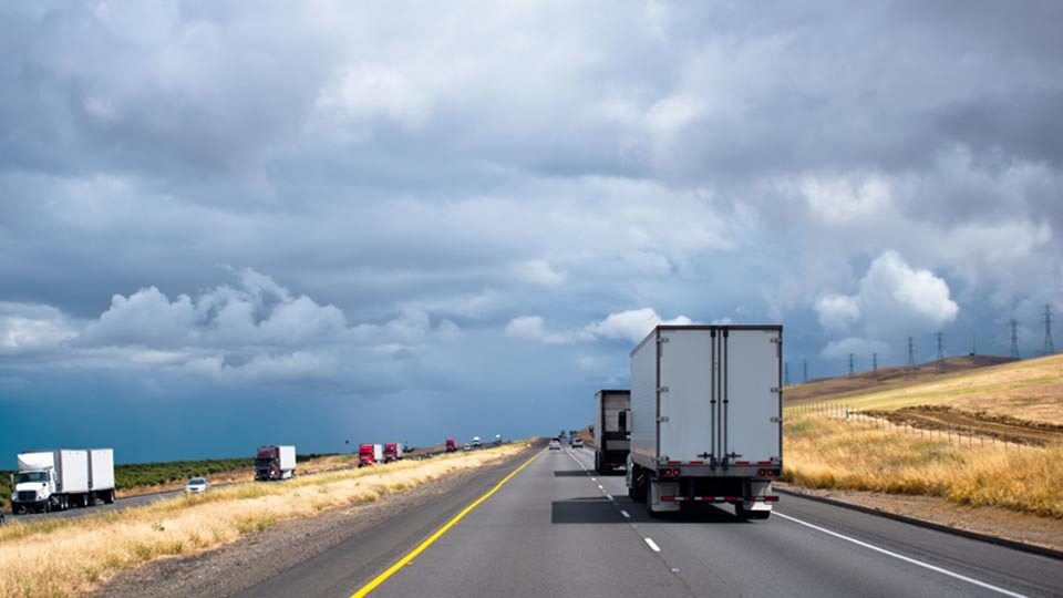 Vehicles driving on road with a cloudy sky 