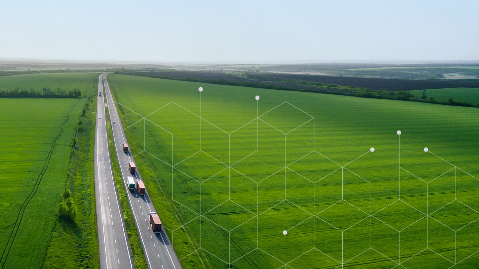 Trucks driving on highway beside green fields