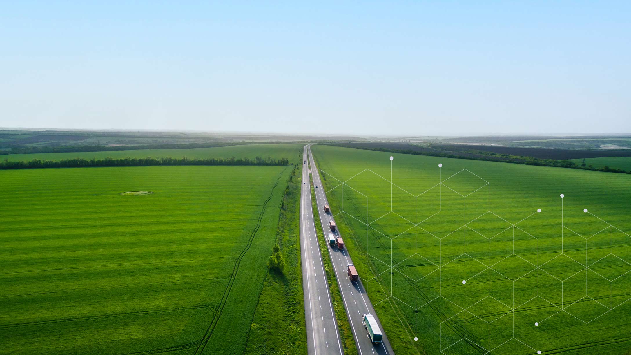 Trucks driving on highway beside green fields