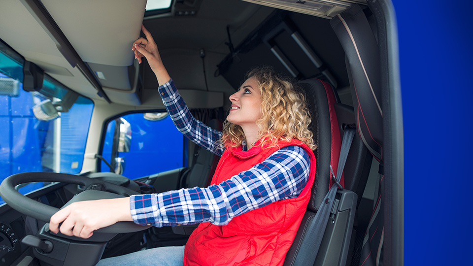 LKW-Fahrerin bedient digitalen Tachographen im Fahrerhaus