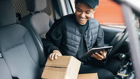 woman checking package in front of delivery van