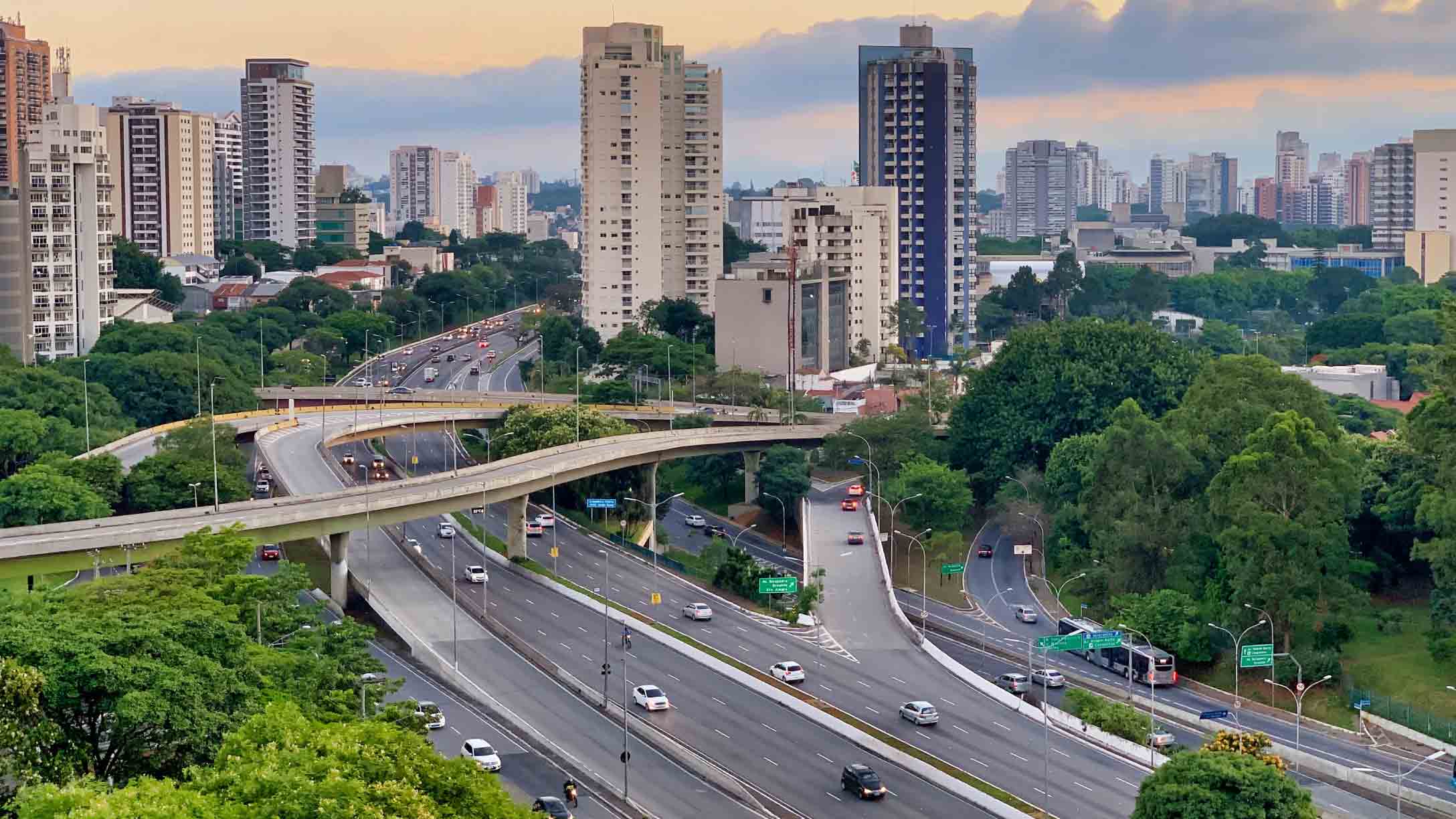 Vista aérea de rodovia urbana em São Paulo com tráfego leve e áreas verdes ao redor, destacando o contexto da segurança viária.