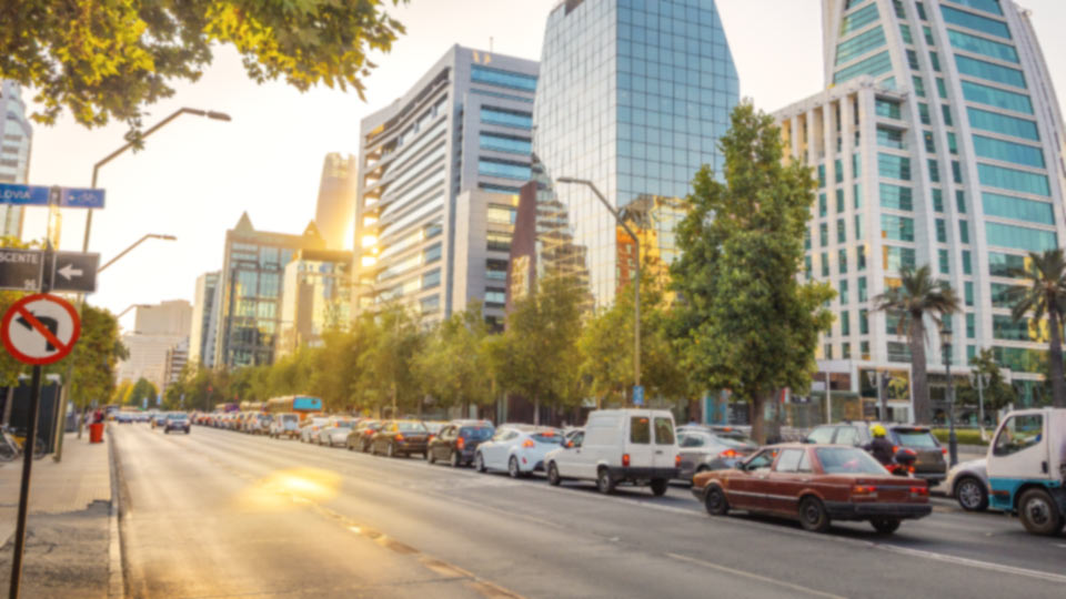 Tráfico vehicular en zona urbana con edificios corporativos, representando los retos de movilidad y seguridad vial en ciudades modernas.