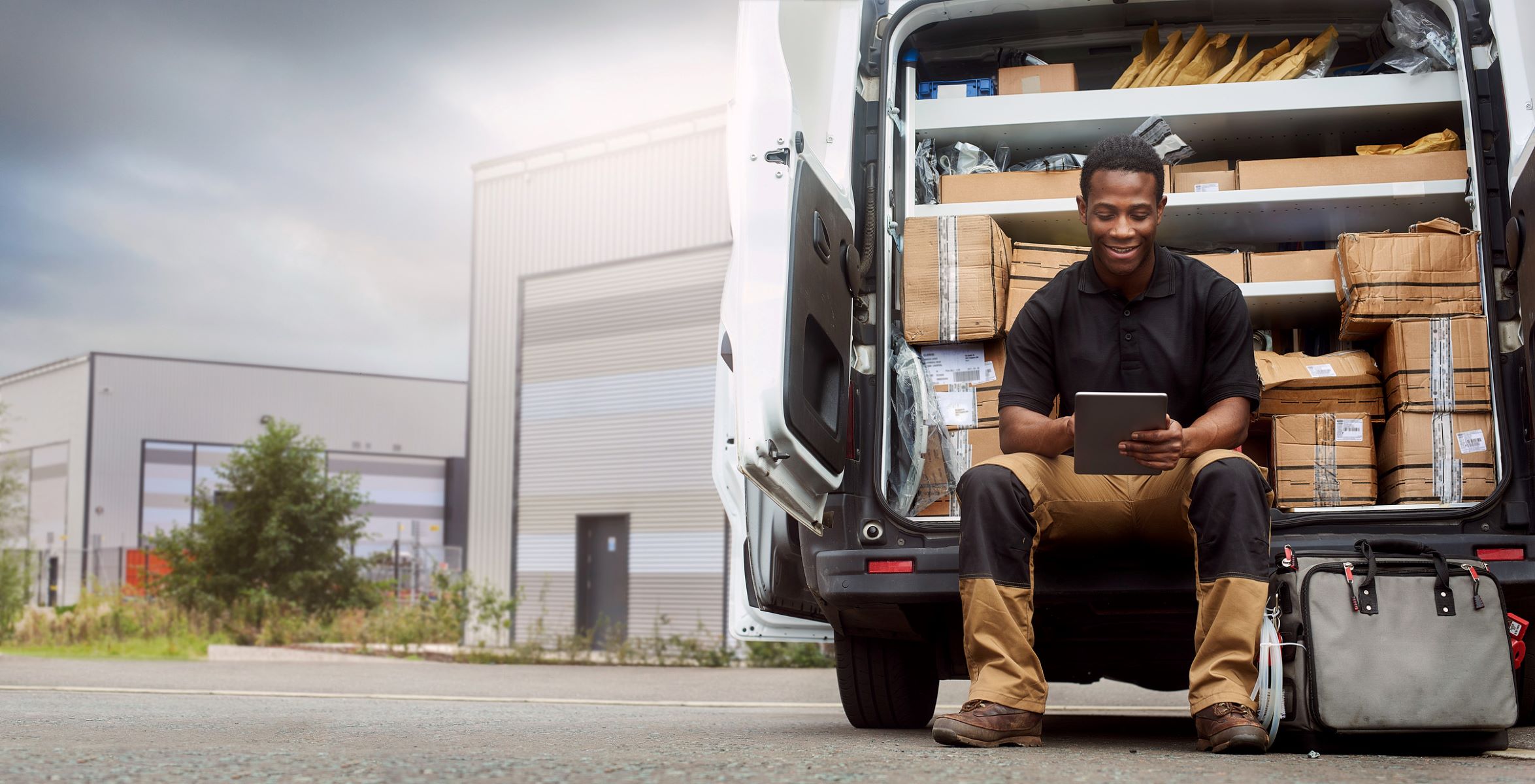 Person sitting at the back of a truck with the an open door full of packages