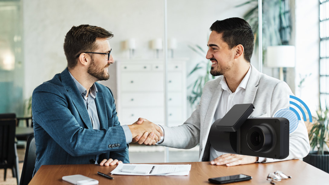 two men shaking hands with the camera on the background