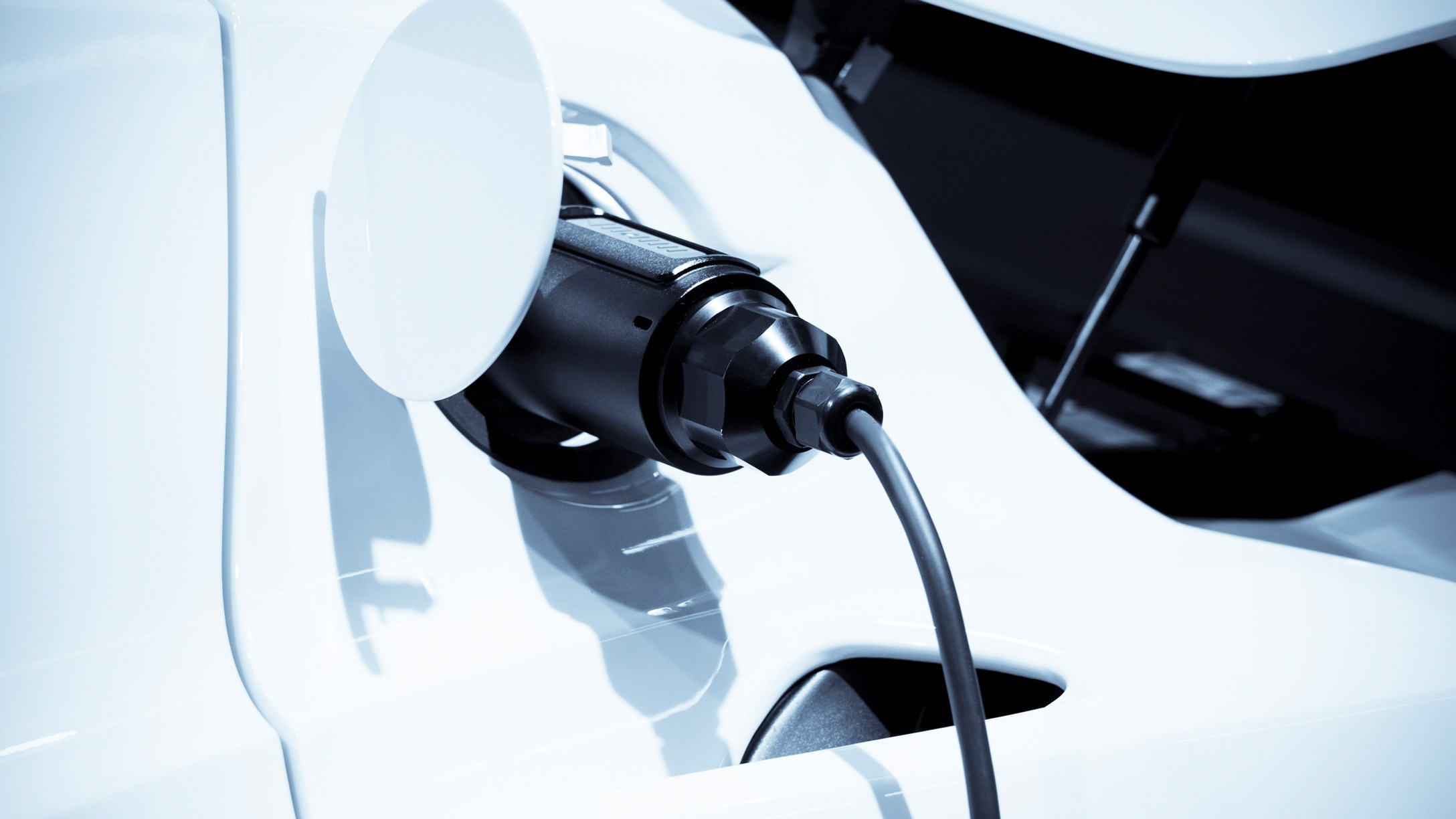 Immagine di un connettore di un veicolo elettrico bianco in ricarica