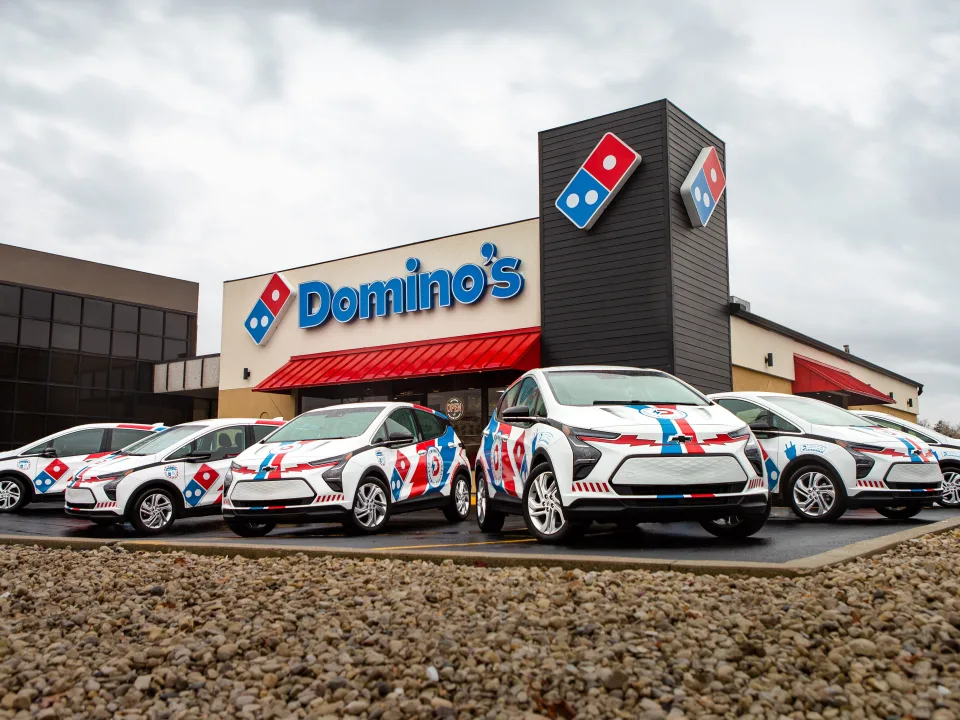 carros na dominos estacionados na frente de uma loja da mesma