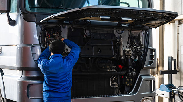 Técnico realizando manutenção preventiva em um caminhão, assegurando o bom funcionamento e a redução de custos na gestão de frotas.