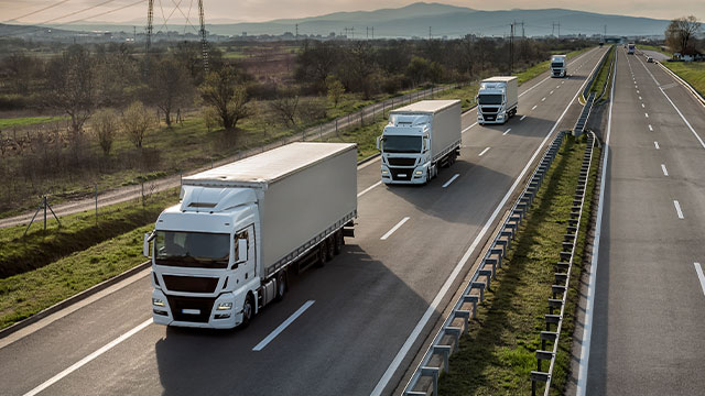 Frota de caminhões em movimento em uma estrada, representando a eficiência da gestão de frotas com telemática e tecnologias avançadas.