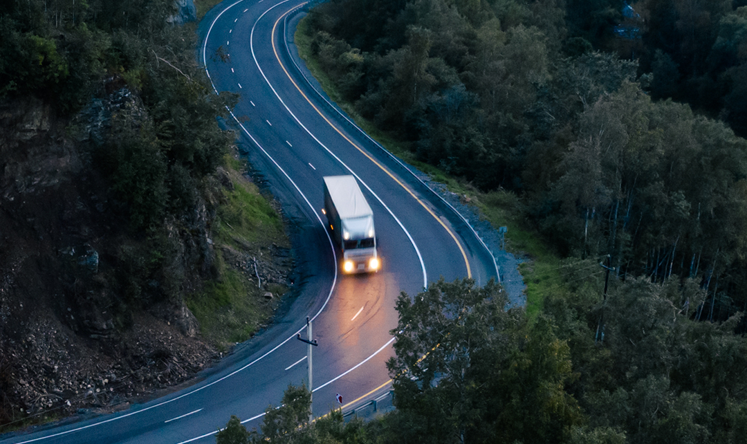 Caminhão em uma estrada sinuosa, ilustrando como a tecnologia de monitoramento da força G da Geotab ajuda a avaliar o comportamento do motorista e a segurança da frota em condições variadas.