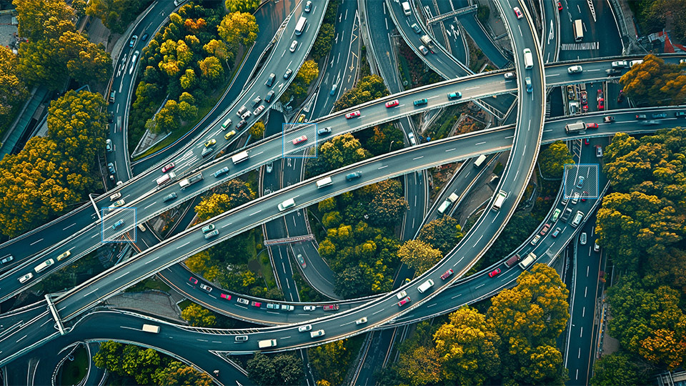 A dynamic aerial photograph, taken from a high, bird's-eye perspective, showing a large and complex highway interchange.