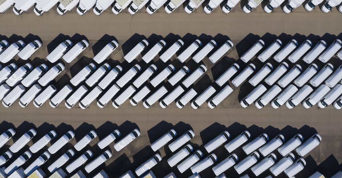 Aerial view of a large fleet of white delivery vans and trucks parked in rows.