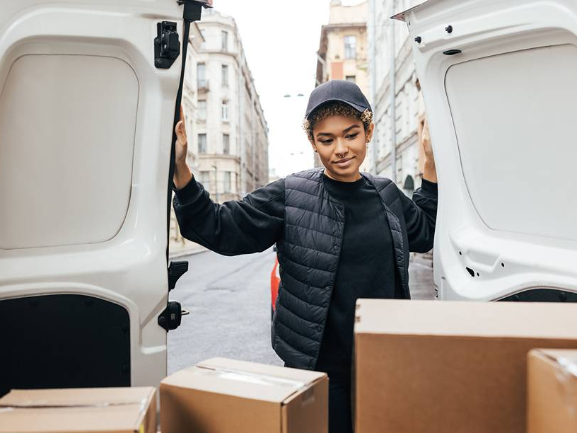 Ein Kurier öffnet die Türen eines Transporters mit Paketen darin.
